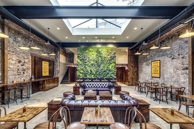 Brick walls chesterfield couches green living wall and skylight in the cafe interior of Botica Del Cafe in New York
