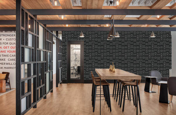 Glyph Henge patterned designer wallpaper with dark grey background and lighter grey patterns positioned in vertical strips on a wall in a commercial office interior